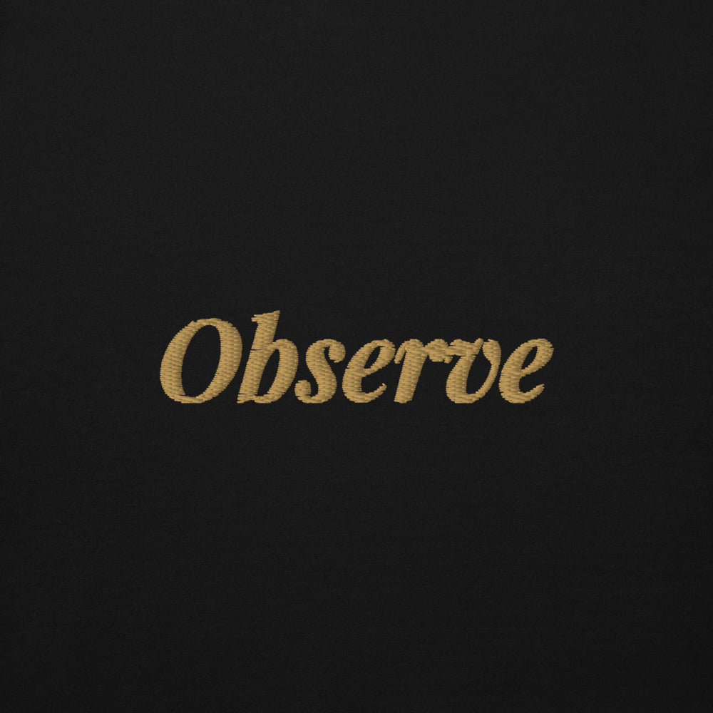 Observe Embroidered Hoodie in Black, close-up of the front embroidery.